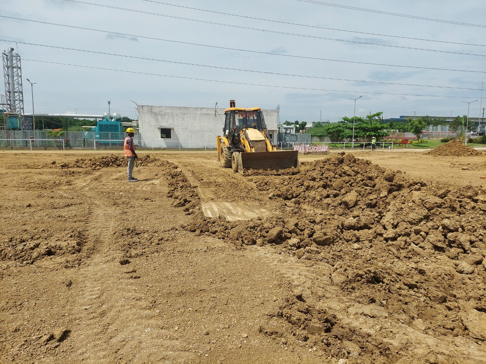 Industrial land grading using a backhoe loader during site development