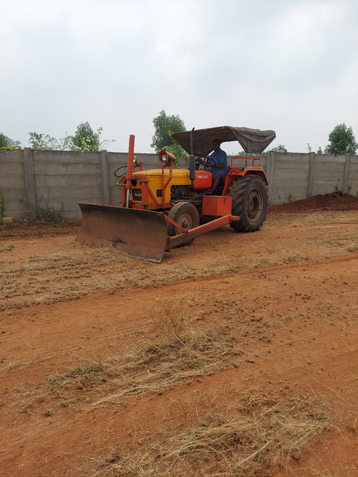 Industrial land leveling with a tractor blade across the open plot