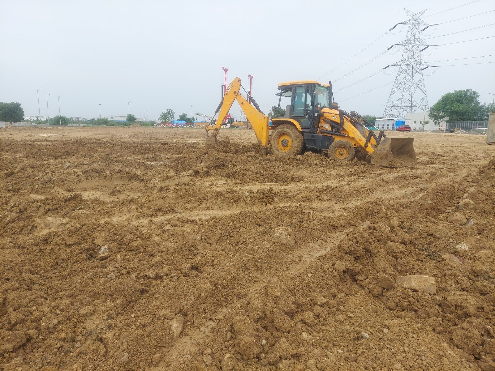 Open plot grading by JCB excavator for industrial site development