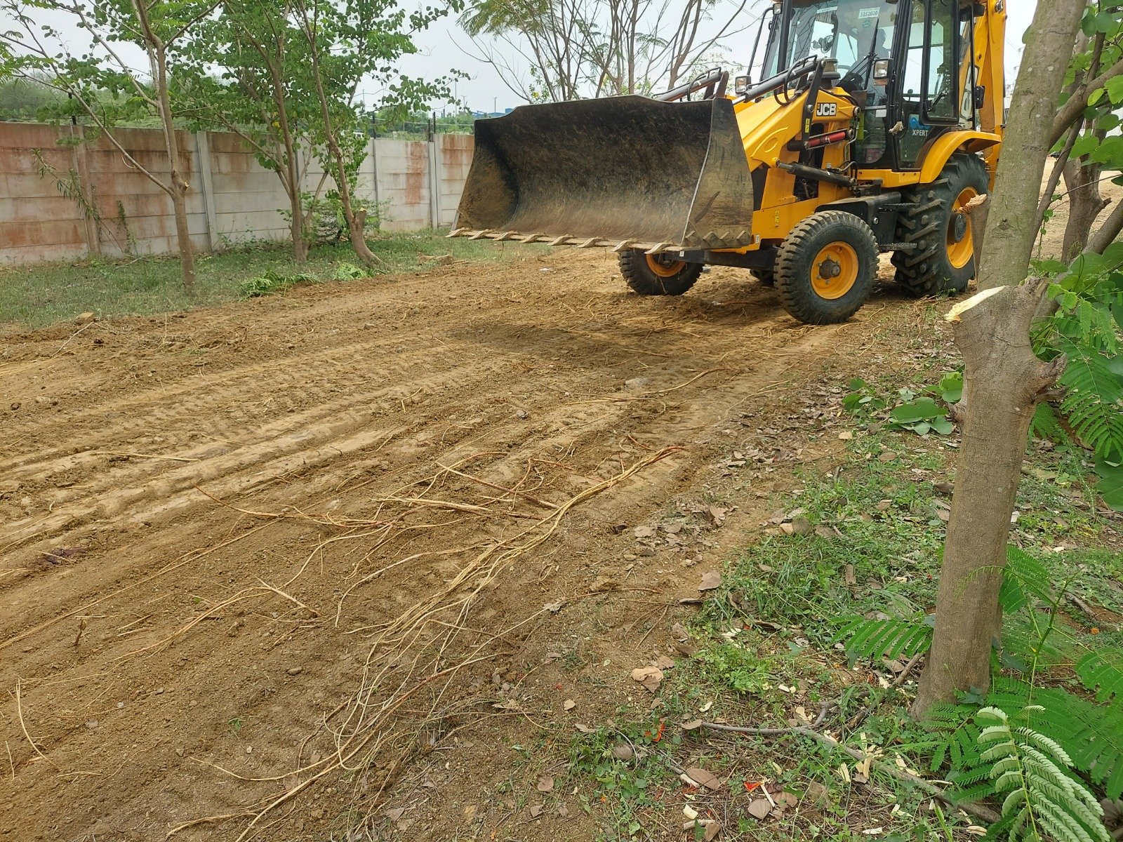 Industrial site clearing and boundary wall construction at the plot perimeter